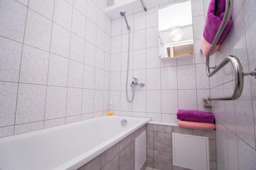 y baño blanco con bañera y toallas púrpuras. en Trumpalaikis būstas Plungėje en Plungė