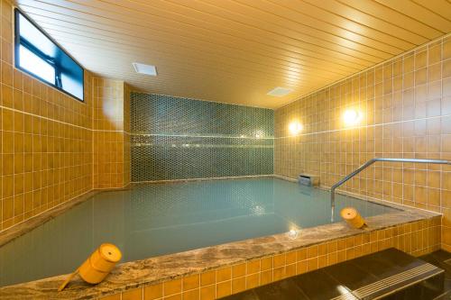 een groot zwembad in een gele betegelde badkamer bij Sanco Inn Kyoto Hachijoguchi Shikinoyu in Kyoto