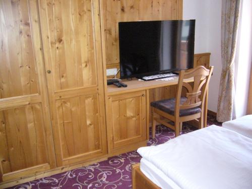 a bedroom with a desk with a television and a chair at Alpenhotel Pfaffenwinkel in Peiting