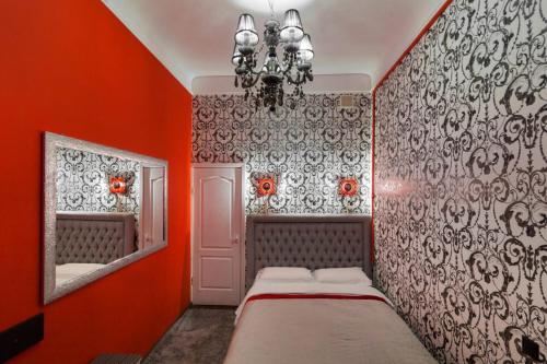 een slaapkamer met oranje muren en een bed en een spiegel bij Cozy studio for couple near Polytechnic University in Lviv