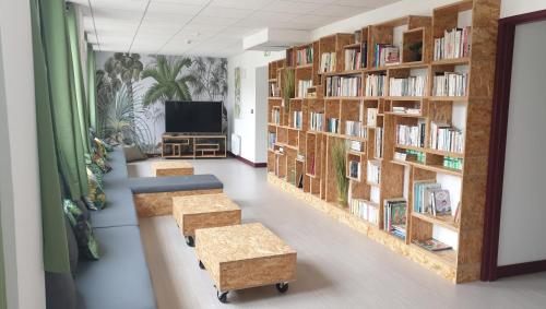 a library with wooden bookshelves and a flat screen tv at Hostel les Terrasses du Roc in Saint-André-de-Roquepertuis