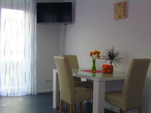 una mesa de comedor con sillas y un jarrón de flores en Murthum Gästeappartments, en Leinfelden-Echterdingen