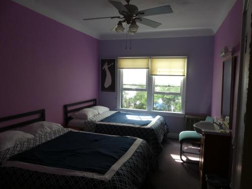Dormitorio púrpura con 2 camas y ventana en Hotel del Flores, en Los Ángeles