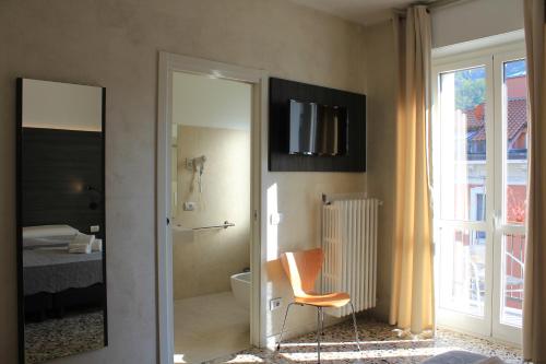 een badkamer met een stoel en een televisie aan de muur bij SoloSonno in Lecco