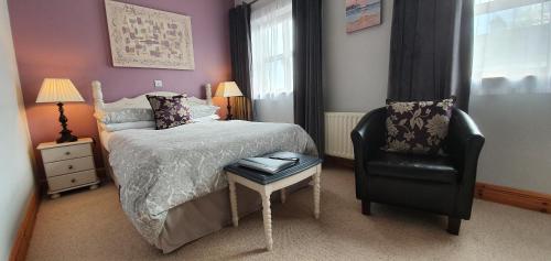 a bedroom with a bed and a black chair at Church View House F56H977 in Gorteen