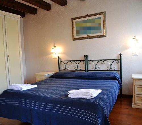 a bedroom with a blue bed with two towels on it at Oceano Mare B&B in Venice