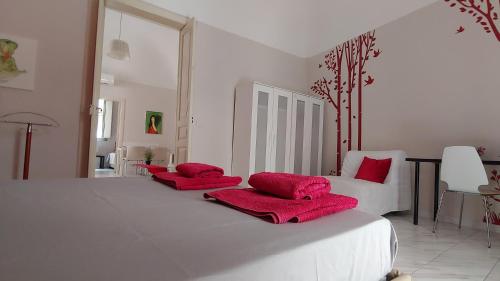 una camera da letto bianca con 2 cuscini rossi su un letto di The Good Place a Catania