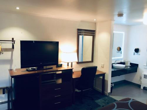 a room with a desk with a television and a chair at Berkshire Inn in Pittsfield
