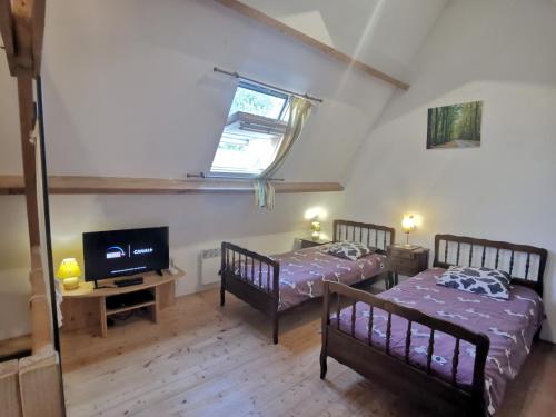 2 Betten in einem Zimmer mit einem TV und einem Fenster in der Unterkunft ferme de Méraville in Nielles-lès-Ardres