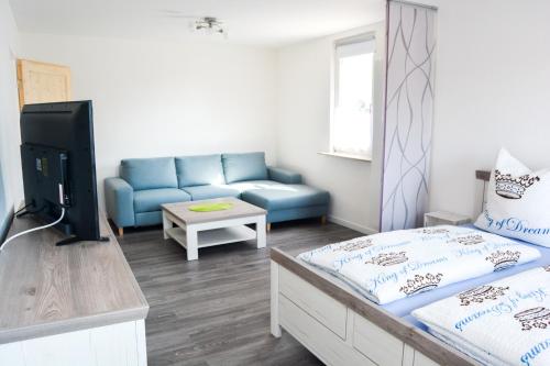uma sala de estar com um sofá azul e uma televisão em Ferienwohnung Landquartier em Schweppenhausen