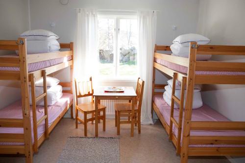 a room with bunk beds with a table and a window at Hunnebostrands vandrarhem Gammelgården in Hunnebostrand