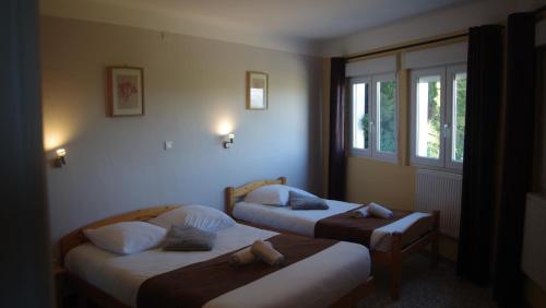 twee bedden in een kamer met twee ramen bij Le Robinson in Pierrelatte
