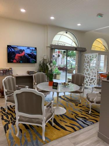 - un salon avec une table et des chaises sur un tapis dans l'établissement Hotel Biney, à Rodez