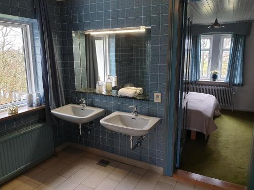 un bagno piastrellato blu con due lavandini e uno specchio di Gørdinglund Manorhouse Mainbuilding a Gørding