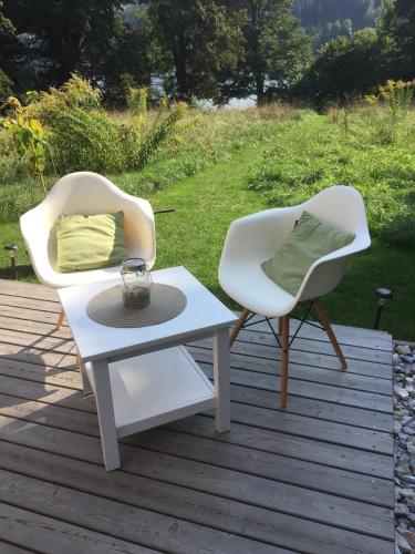 two white chairs and a table on a deck at refugium am see in Seeboden