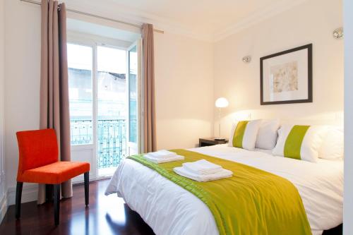 een slaapkamer met een bed, een stoel en een raam bij Baxia-Chiado Apartment with Incredible view in Lissabon