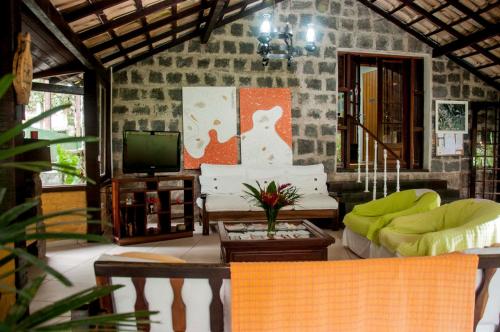 a living room with a couch and a tv at Pousada Valle dos Pássaros in Penedo