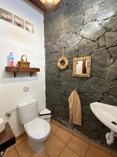 a bathroom with a stone wall and a toilet and a sink at Villa Feel in Tías