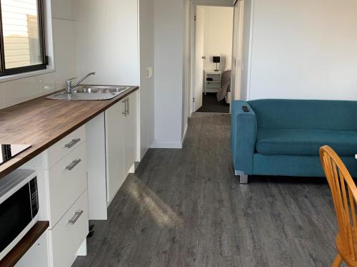 a kitchen with a sink and a blue couch at Swansea Holiday Park Tasmania in Swansea