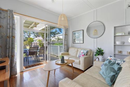a living room with a couch and a table at Calm Waters Waterfront Cottages in Sussex inlet