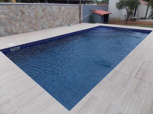 a swimming pool with blue water and a wooden deck at Búzios Casa de Família - Bosque de Geribá in Búzios