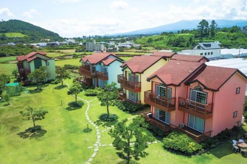 a group of houses in a field with trees at Jeju Time-Travel Pension in Jeju