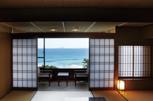 
a room with a table, chairs and a window at Imaiso in Kawazu
