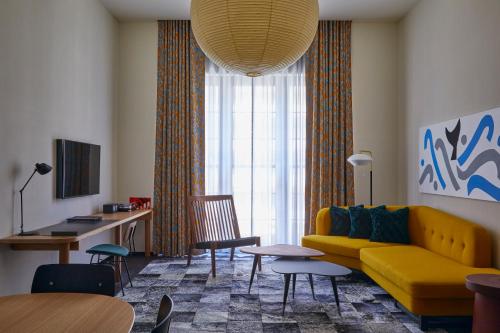 a living room with a yellow couch and a table at Ace Hotel Kyoto in Kyoto