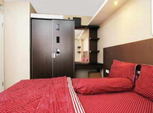 a bedroom with a red bed with a metal door at Kalibata city by Sang Living in Jakarta