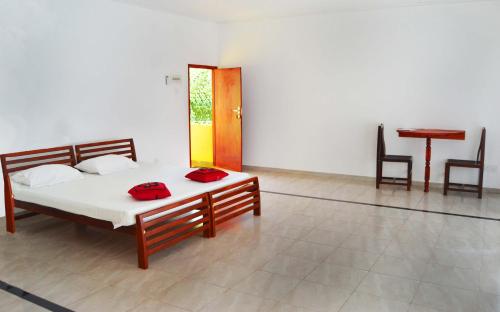 a bedroom with a bed with red pillows and a table at The Citadel Guest House in Hikkaduwa