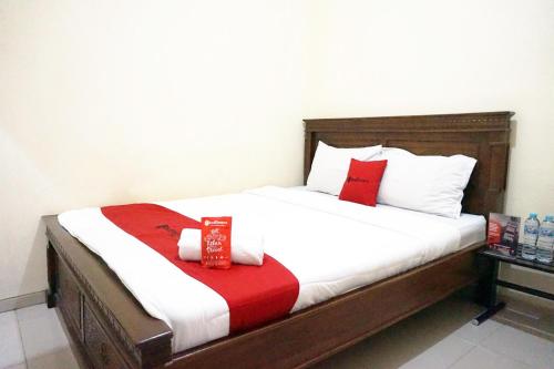 a bed with red and white pillows on it at RedDoorz @ Jalan Kedawung in Malang