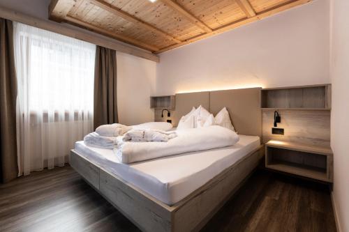 um quarto com uma cama grande e lençóis brancos em Apartments & Garnì Pre Da Nai em La Villa