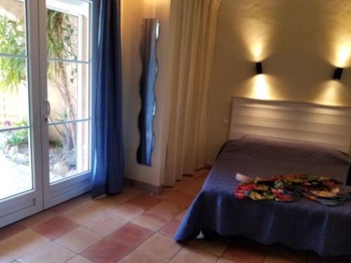 une chambre avec un lit et une grande fenêtre dans l'établissement La Villa Les Hespérides, à Grimaud