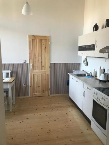a kitchen with white appliances and a wooden floor at Apartmán U Borovice in Rychnov nad Kněžnou