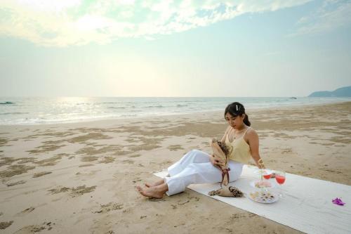 a woman sitting on a surfboard on the beach at Baan Imm Sook Resort in Chao Lao Beach