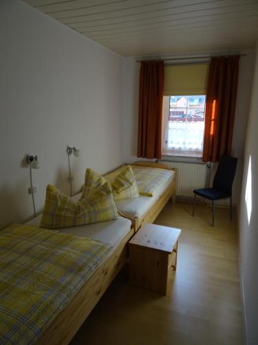 a room with two beds and a chair and a window at Ferienwohnung Bäckerei Förster in Bad Schandau