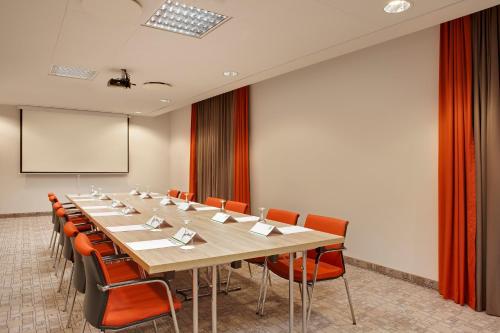 a large conference room with a long table and orange chairs at Holiday Inn Berlin City East Side by IHG in Berlin