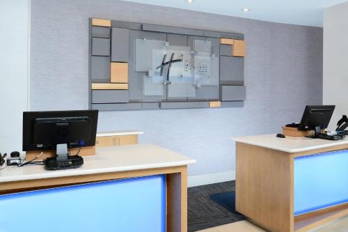 an office with two desks with a monitor and a tv at Holiday Inn Express & Suites Raleigh Durham Airport at RTP by IHG in Durham