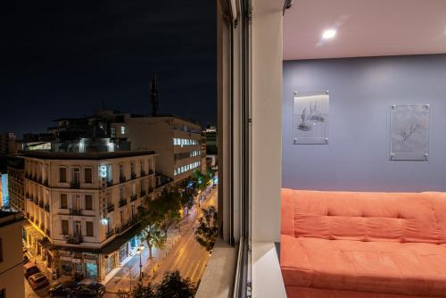 een raam met uitzicht op de stad 's nachts bij AthinA STREETAPARTMENTS in Athene