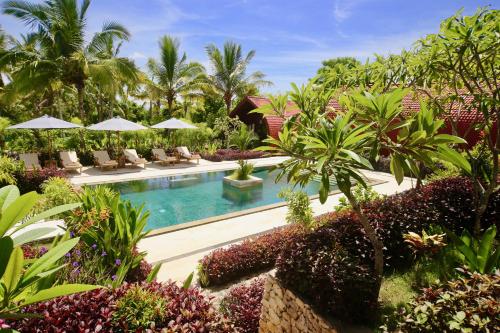 a pool at a resort with chairs and trees at Jungle Paradise in Nusa Penida