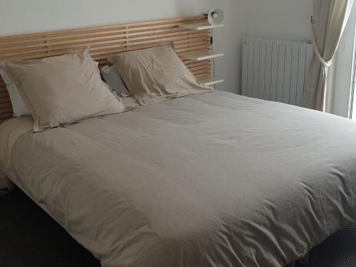 Elle comprend un grand lit avec des draps et des oreillers blancs. dans l'établissement Ménez Rhun, à Combrit