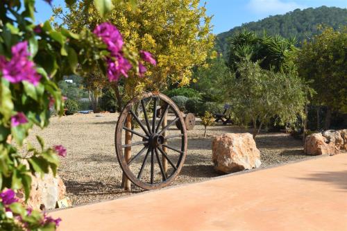 a woodenoked wheel in a garden with rocks and trees at Agroturismo Sa Marina - Adults Only in Cala Boix