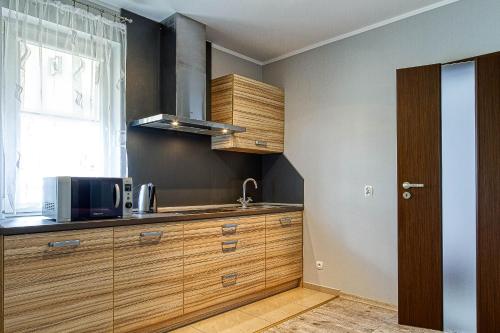 a kitchen with wooden cabinets and a microwave at Apartamenty Piła in Piła