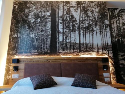 una camera da letto con un murale della foresta sul muro di Albergo Silvana a Ledro