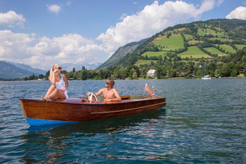 two women sitting on a boat on a lake at Auhof Wirtshaus & Suiten in Kaprun