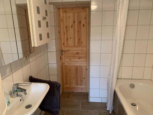 baño con lavabo, bañera y puerta en Ferienhaus Ramersdorf en Kollnburg