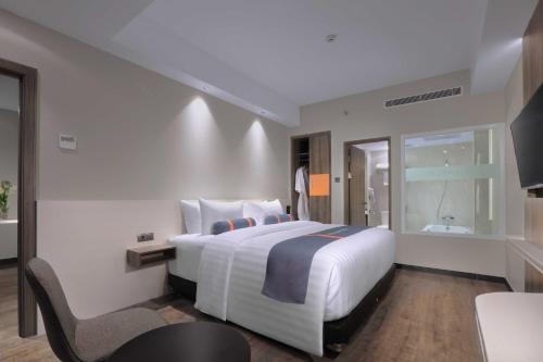 a bedroom with a large white bed and a chair at Harper Wahid Hasyim Medan by ASTON in Medan