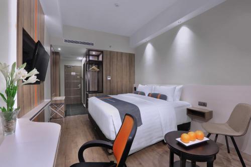 a hotel room with a bed and a table with oranges on a tray at Harper Wahid Hasyim Medan by ASTON in Medan