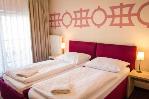 two beds in a hotel room with a red headboard at Akord in Ostrava
