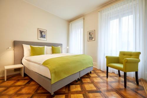 a bedroom with a large bed and a chair at Hotel Schmid & Alfa in Brunnen
